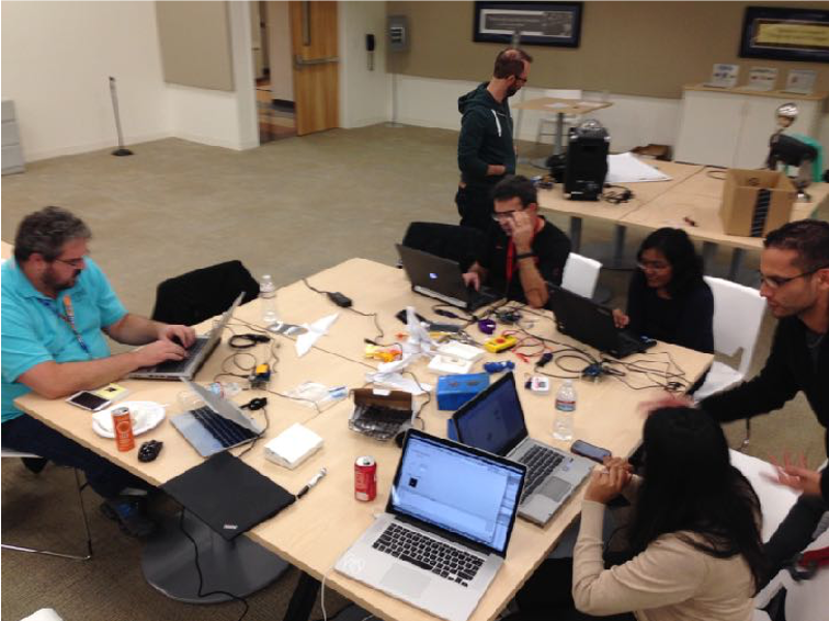 people sitting around at table during hackathon working on computers